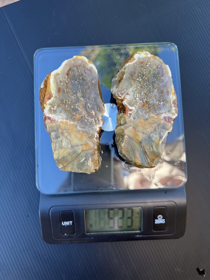 Large matched pair of cream and grey agate nodule slices on a scale showing 533g, with wing-like sculptural shape